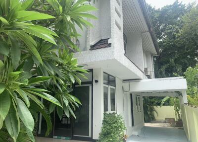 Exterior view of a modern two-story house with lush greenery