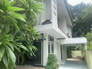 Exterior view of a modern two-story house with lush greenery