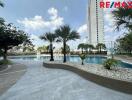 Outdoor swimming pool area with surrounding palm trees and high-rise building