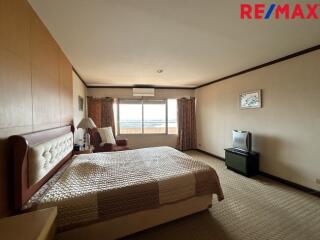 Spacious bedroom with a large window, bed, TV, and bedside table