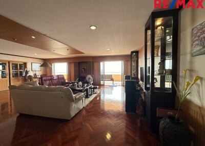 Spacious living room with wooden flooring, comfortable seating, and large windows.