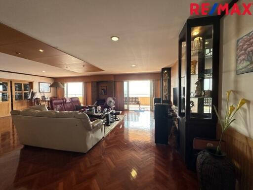 Spacious living room with wooden flooring, comfortable seating, and large windows.