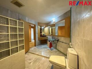 Spacious bathroom with tiled walls and glass block partition