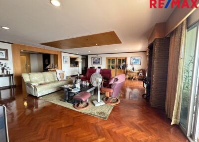 Spacious living room with seating area, wooden flooring, and large windows