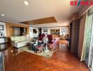 Spacious living room with seating area, wooden flooring, and large windows