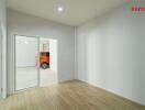 Vacant room with wooden flooring and a sliding glass door leading to a garage with an orange car