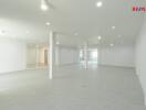 Spacious empty room with white walls and tile flooring