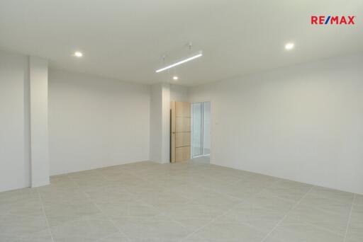 Spacious living room with minimalist design, tile flooring, and ample lighting