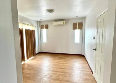 Empty bedroom with wooden floor, air conditioning unit, and two windows with blinds