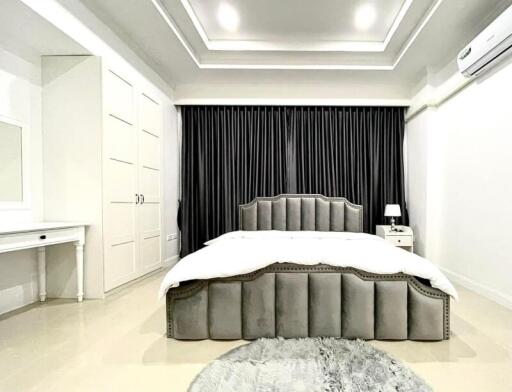 Spacious and modern bedroom with grey bed and black curtains