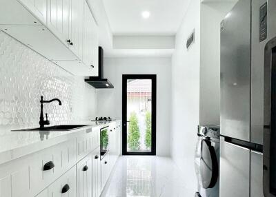 Bright modern kitchen with white cabinetry, countertop, and appliances