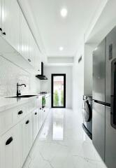 Bright modern kitchen with white cabinetry, countertop, and appliances