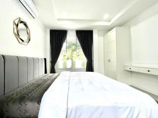 Bright bedroom with a large bed, black curtains, and white built-in closet