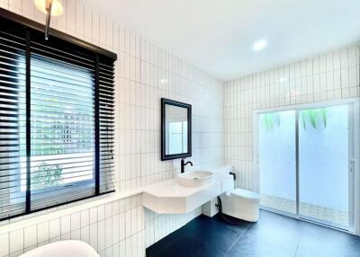 Modern bathroom with white tiles, large mirror, and black accents