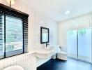 Modern bathroom with white tiles, large mirror, and black accents