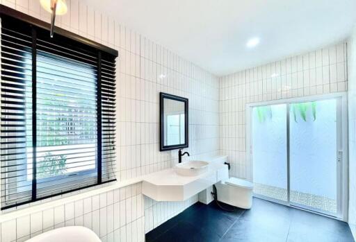 Modern bathroom with white tiles, large mirror, and black accents