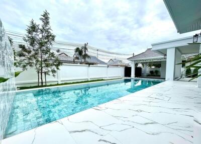 Outdoor view of a pool area with clear water, surrounding tiles, and part of an adjacent building