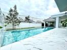 Outdoor view of a pool area with clear water, surrounding tiles, and part of an adjacent building