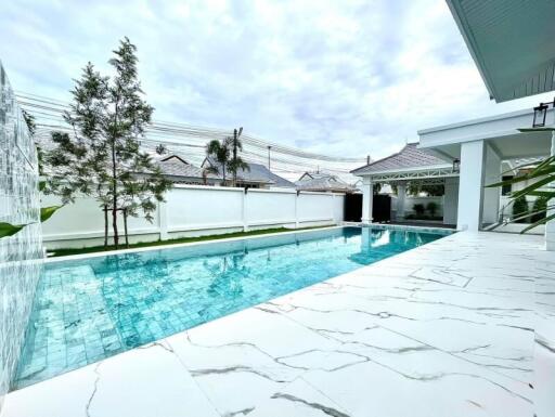 Outdoor view of a pool area with clear water, surrounding tiles, and part of an adjacent building