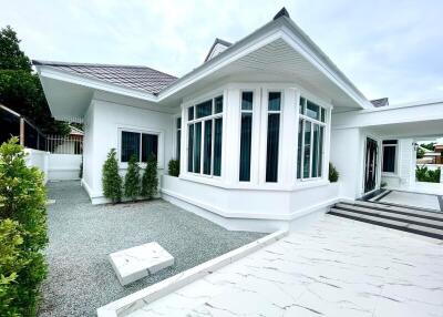 Exterior view of a modern white house with large windows and landscaped surroundings