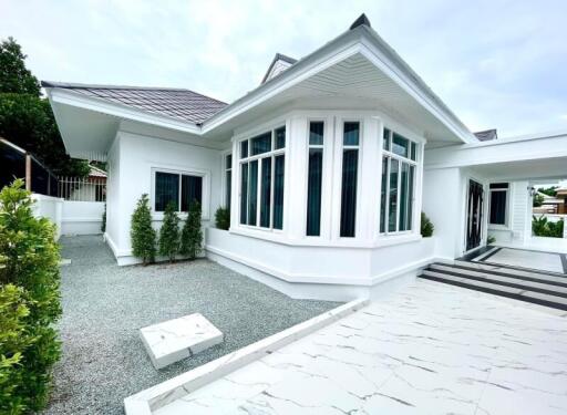 Exterior view of a modern white house with large windows and landscaped surroundings