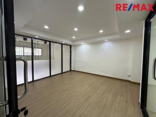 Modern empty room with wooden flooring, ceiling lights, and large glass partitions