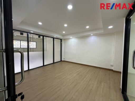 Modern empty room with wooden flooring, ceiling lights, and large glass partitions