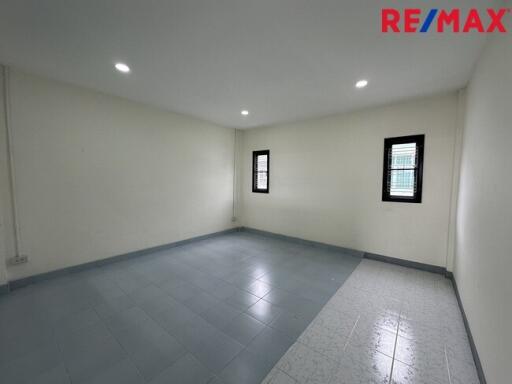 Empty bedroom with tiled floor and two windows