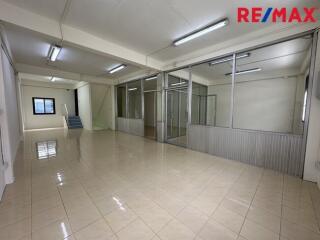 Spacious office area with tiled floors, fluorescent lighting, and glass partitions