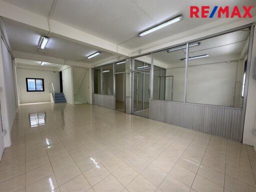 Spacious office area with tiled floors, fluorescent lighting, and glass partitions