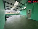 Interior view of a spacious, empty room with green walls and a metal roof