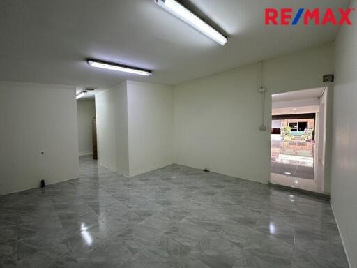 Spacious empty room with tiled floor and fluorescent lighting