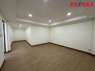 Spacious empty room with wooden flooring and recessed lighting