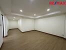 Spacious empty room with wooden flooring and recessed lighting