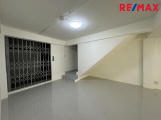 Spacious living area with bright lighting and stairs to upper floor