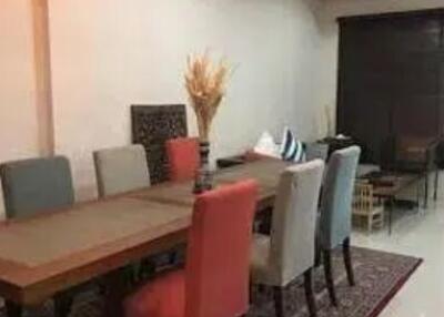 Dining room with a long wooden table, mismatched chairs, and a decorative rug