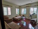 Cozy living room with multiple seating options and wooden flooring