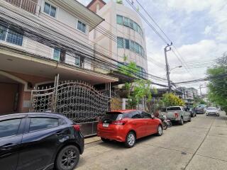 Street view of residential buildings with parked cars