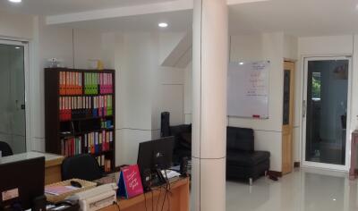 Office area with desks, computer, bookshelf, and seating area
