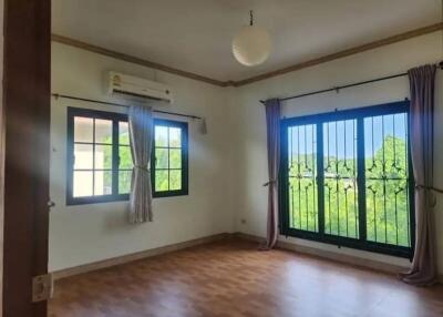 Spacious bedroom with large windows and wooden flooring