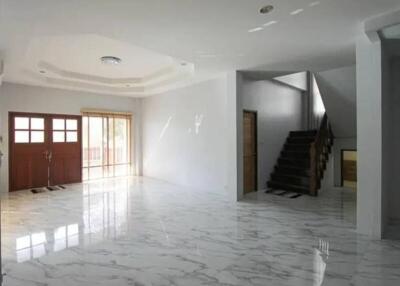 Spacious living room with marble floors, wooden staircase, and large windows