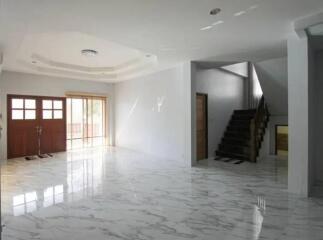 Spacious living room with marble floors, wooden staircase, and large windows