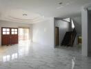 Spacious living room with marble floors, wooden staircase, and large windows