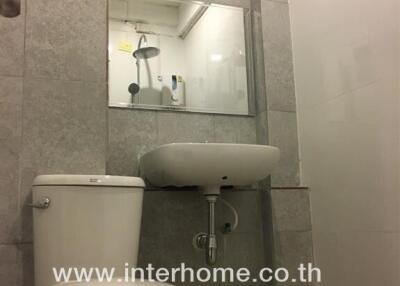 Modern bathroom with toilet, sink, and shower reflected in mirror