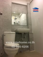 Modern bathroom with toilet, sink, and shower reflected in mirror