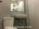 Modern bathroom with toilet, sink, and shower reflected in mirror