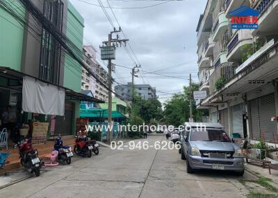 Street view showing buildings, vehicles, and nearby shops