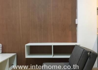 Modern living room with wooden flooring, a minimalist armchair, and a wall-mounted shelving unit