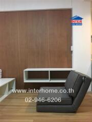 Modern living room with wooden flooring, a minimalist armchair, and a wall-mounted shelving unit