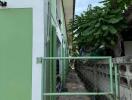 Side exterior of a building with green walls and a metal gate